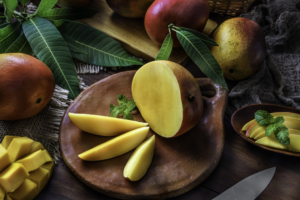 Healthy eating themes. Tropical Fruits: Sliced mangos in a clay rustic plate on a wooden table in rustic kitchen