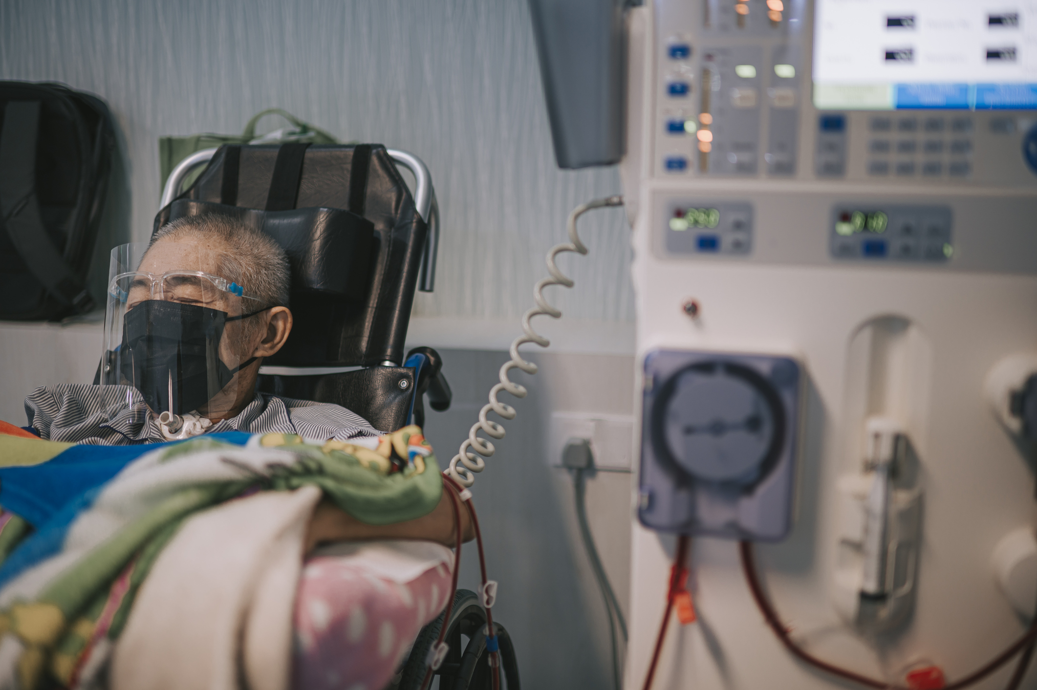 asian chinese senior man in wheelchair with face shield , face mask under dialysis treatment in hospital