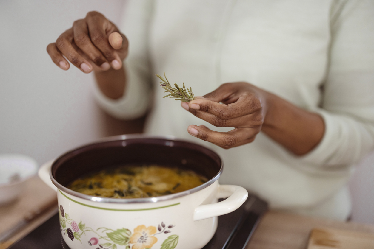 Hands with green ingredients and spicy herbs cooking healthy food on the kitchen