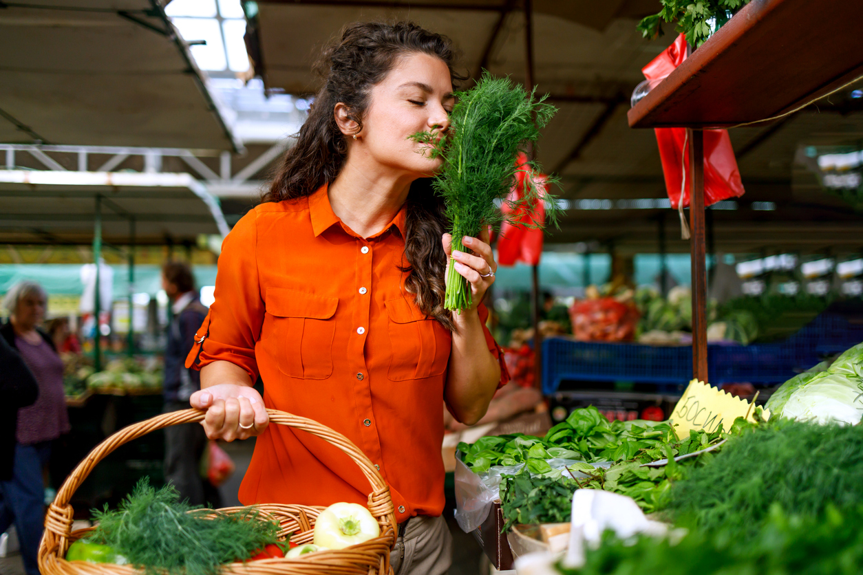 A woman in her middle years is captured in the act of sifting through leafy greens, clearly taking her time to pick the freshest options